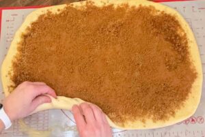 homemade cinnamon roll dough being rolled up