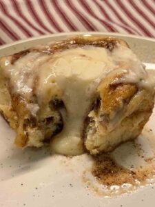 cinnamon roll on a plate with lots of icing